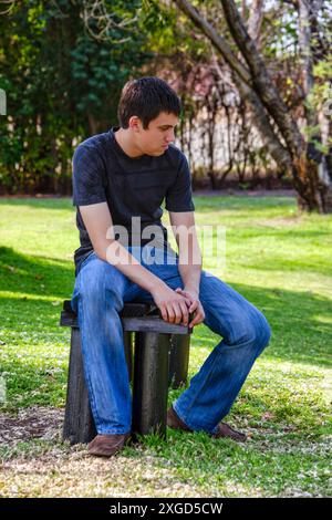 giovane solo seduto su una panchina nel parco Foto Stock