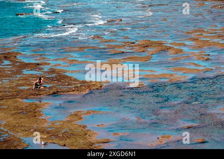 Cádiz, Spagna - 14 aprile 2024: Una persona, non identificabile, apprezza una giornata in spiaggia, seduta su una sedia incastonata tra rocce e mare a la Caleta Foto Stock