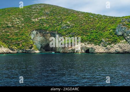 Yacht ormeggiato all'esterno della formazione di grotte su una collina rocciosa con piantagione verde che si estende fino al mare, Zante, Isole Ionie, Isole greche, Grecia, EUR Foto Stock