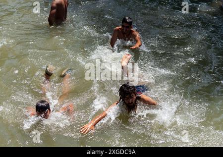 Kashmir, India. 8 luglio 2024. I residenti del Kashmir hanno visto nuotare in un canale d'acqua durante una giornata calda a Pulwama. Quest'anno il Kashmir ha affrontato sfide climatiche senza precedenti, segnate da temperature massime record a Srinagar e in tutta la regione. Gli esperti attribuiscono questi eventi meteorologici estremi agli impatti più ampi del cambiamento climatico. I cambiamenti nei modelli monsonici e la presenza irregolare di disturbi occidentali hanno interrotto i cicli meteorologici tradizionali della regione, portando a precipitazioni irregolari e fluttuazioni di temperatura. Credito: SOPA Images Limited/Alamy Live News Foto Stock