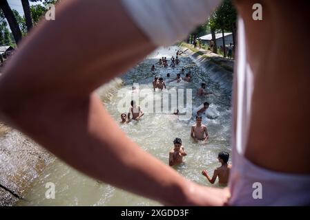 I residenti del Kashmir hanno visto nuotare in un canale d'acqua durante una giornata calda a Pulwama. Quest'anno il Kashmir ha affrontato sfide climatiche senza precedenti, segnate da temperature massime record a Srinagar e in tutta la regione. Gli esperti attribuiscono questi eventi meteorologici estremi agli impatti più ampi del cambiamento climatico. I cambiamenti nei modelli monsonici e la presenza irregolare di disturbi occidentali hanno interrotto i cicli meteorologici tradizionali della regione, portando a precipitazioni irregolari e fluttuazioni di temperatura. Questi cambiamenti non solo influenzano i modelli agricoli e le risorse idriche, ma anche pongono segni Foto Stock