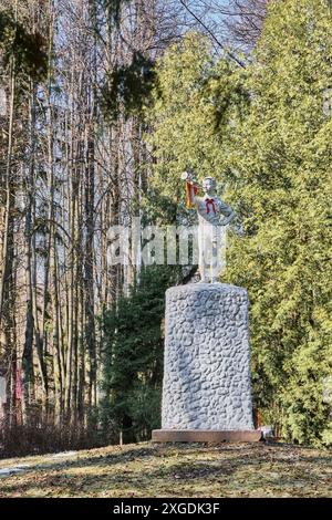 Mosca, Russia - 5 aprile 2024: Scultura di un giovane bugler in cravatta rossa pioniere su piedistallo. Monumento standard dell'epoca sovietica nel vecchio parco. Paesaggio primaverile. Foto Stock