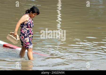 SAMUT PRAKAN, TAILANDIA, febbraio 02 2024, Una donna cammina attraverso una strada allagata Foto Stock