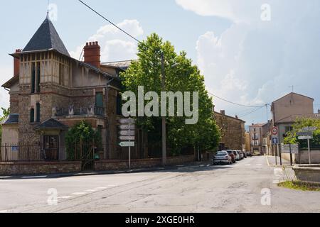 Langeac, Francia - 28 maggio 2023: Una vista di una casa in pietra con una torre, situata su una strada fiancheggiata da alberi nella città di Langeac, Francia. Foto Stock