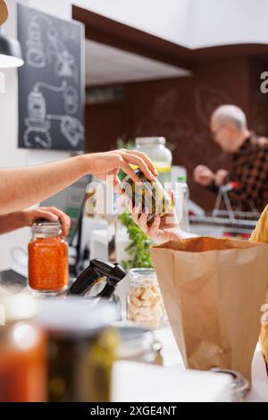 Cliente al banco cassa nel negozio zero rifiuti, a pagamento per prodotti vegani venduti dal magazzino. Cliente che acquista cibo sano nel negozio di quartiere locale utilizzando solo sacchetti di carta Foto Stock