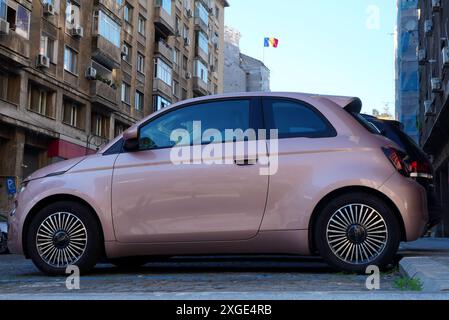 Bucarest, Romania - 16 giugno 2024: Vista laterale ravvicinata della nuova auto rosa Fiat 500 parcheggiata vicino all'edificio degli appartamenti Foto Stock