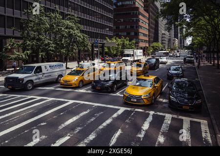 Vista ad alto angolo dei taxi gialli e del traffico cittadino ad un incrocio sulla 6th Avenue a Midtown Manhattan, New York City, USA, in una giornata di sole Foto Stock