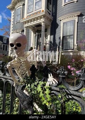 Uno scheletro decorato di Halloween si affaccia su una recinzione di una casa storica in un giorno d'autunno è Salem, Massachusetts Foto Stock