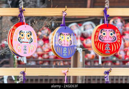 gunma, takasaki - gennaio 25 2024: Placche ema votive buddiste raffiguranti volti di bambole Daruma giapponesi con vari messaggi di preghiera a seconda del colo Foto Stock