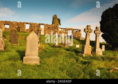 Le rovine di un'antica chiesa in pietra su una collina si affacciano sul cimitero della chiesa. Le date di croce variano da completamente erose e illeggibili a 1800 a 201 6. Foto Stock