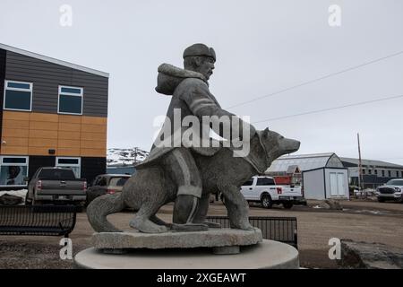 Scultura in pietra di un uomo e un cane Inuit nell'edificio RCMP sulla Federal Road a Iqaluit, Nunavut, Canada Foto Stock