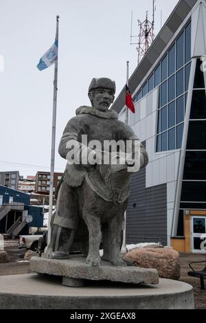 Scultura in pietra di un uomo e un cane Inuit nell'edificio RCMP sulla Federal Road a Iqaluit, Nunavut, Canada Foto Stock