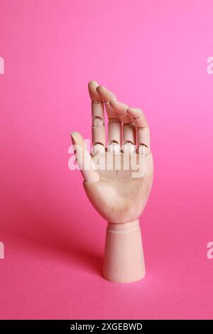 Modello a mano in legno su sfondo rosa. Parte manichino Foto Stock