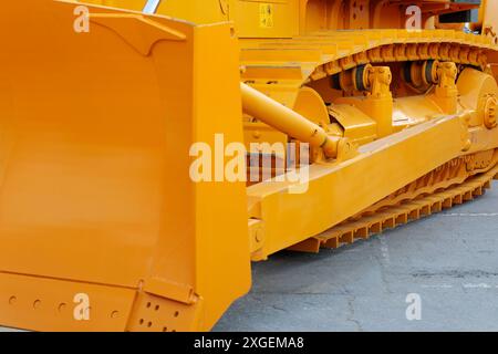 Vista laterale ravvicinata di un bulldozer pesante cingolato. Attrezzature per l'edilizia industriale. Messa a fuoco selettiva. Foto Stock