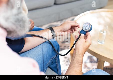 Misurazione della pressione sanguigna, anziano che usa lo sfigmomanometro a casa Foto Stock