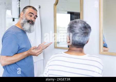 Una coppia anziana che parla e si guarda nello specchio del bagno Foto Stock