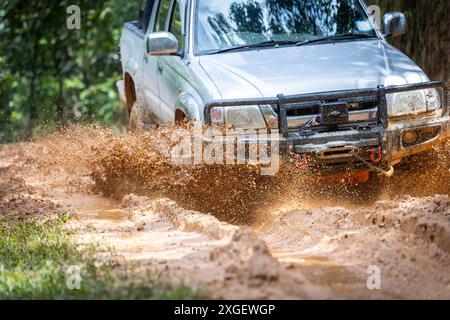 Auto che corrono su strade fuoristrada e che spruzzano fango su sentieri naturali. Guida fuoristrada su strade fangose. SUV fuoristrada 4x4 cavalca tra fangose pozzanghere, fuoristrada Foto Stock