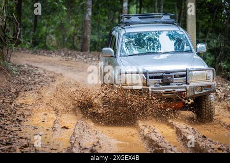 Auto che corrono su strade fuoristrada e che spruzzano fango su sentieri naturali. Guida fuoristrada su strade fangose. SUV fuoristrada 4x4 cavalca tra fangose pozzanghere, fuoristrada Foto Stock