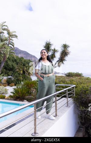 Donna sorridente in tuta verde che gode di una vacanza all'aperto con vista panoramica sulle montagne e spazio fotocopie Foto Stock