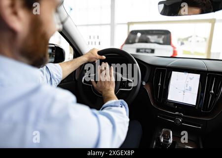 Un uomo d'affari guida un'auto all'interno dello showroom della concessionaria con schermo di navigazione Foto Stock