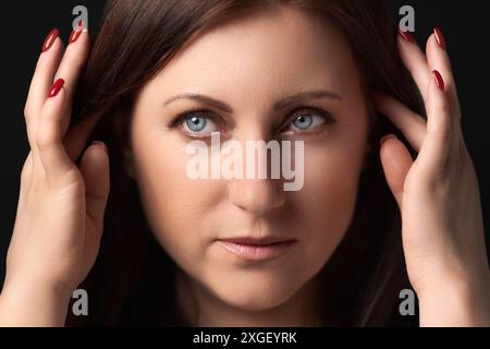 Primo piano estremo di una donna premurosa con problemi personali nella sua mente. Colpo di testa di una donna adulta con mal di testa, mani sollevate vicino alla testa e guardando awa Foto Stock