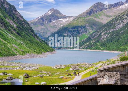 Scenario di montagne con un lago e due ciclisti su un sentiero, natura verde e cielo blu, Klein Tibet, Zillertal, Austria Foto Stock