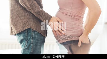 Close up of pregnant mother and father, hugging the tummy, Caucasian Foto Stock