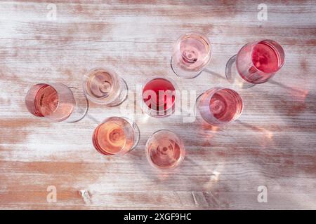 Molte sfumature di vino rosa, stesa piatta sopra la testa con vari bicchieri da vino su uno sfondo di legno Foto Stock