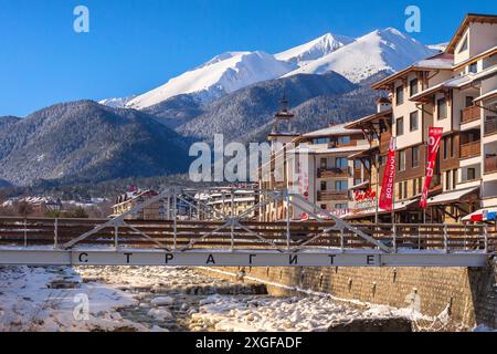 Bansko, Bulgaria, 28 gennaio 2021: Fiume Glazne nella città bulgara, case alberghiere e cime innevate dei monti Pirin Foto Stock