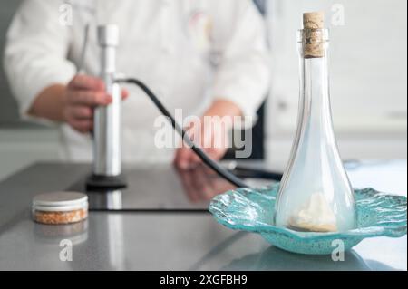 Ottimo chef del ristorante, che fuma un piatto con sofisticati utensili da cucina. Foto di alta qualità Foto Stock