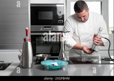 Raffinato ristorante chef preparare piatti deliziosi con sofisticati utensili in cucina commerciale. Foto di alta qualità Foto Stock