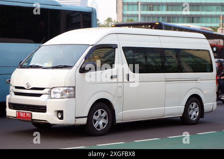 Auto su strada, minivan di lusso e comfort Toyota HiAce di colore bianco presso il quartiere commerciale e commerciale Bundarah HI, Giacarta, Indonesia Foto Stock