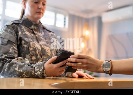 Personale militare militare in uno smartphone di scansione uniforme con mano protesica in clinica, spazio copia Foto Stock