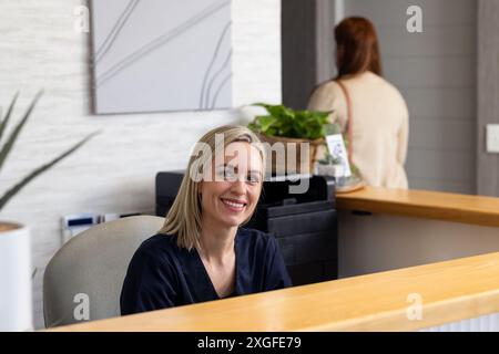 Accoglienza dei pazienti, receptionist sorridente alla reception della clinica medica Foto Stock