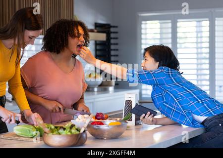 Preparando il pasto, tre donne amiche cucinano insieme e si divertono in cucina Foto Stock