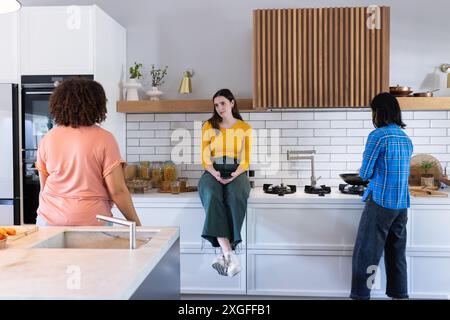 Parlando in cucina, tre donne amiche che conversano casualmente mentre cucinano Foto Stock