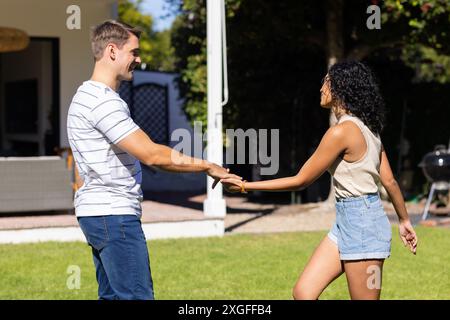 Giovane coppia che si tiene per mano e danzano insieme nel giardino del cortile Foto Stock