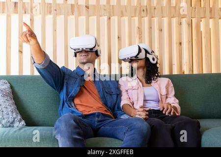 Utilizzando occhiali VR, giovani coppie che vivono la realtà virtuale sul divano Foto Stock