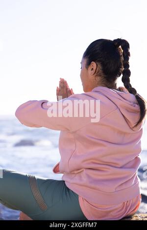 Meditazione sull'oceano, donna matura che pratica yoga e tecniche di rilassamento Foto Stock