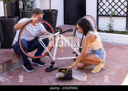 Riparazione di biciclette, giovani coppie che lavorano insieme con il kit attrezzi all'aperto Foto Stock