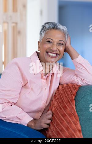 Donna anziana sorridente che si rilassa sul divano e si diverte a casa Foto Stock