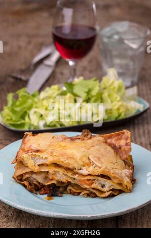 Lasagne con insalata su legno scuro Foto Stock