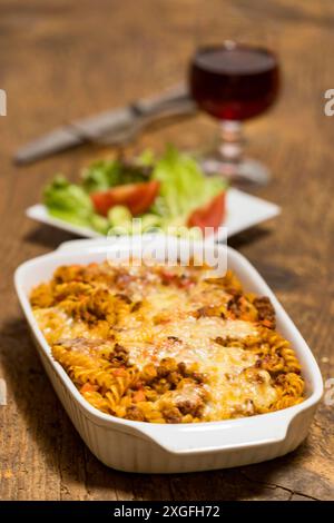 Pasta gratinata con insalata su legno Foto Stock