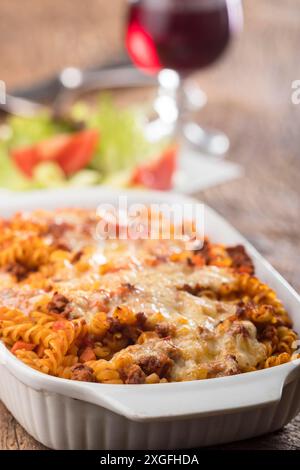 Pasta gratinata con insalata su legno Foto Stock