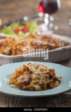 Pasta gratinata con insalata su legno Foto Stock