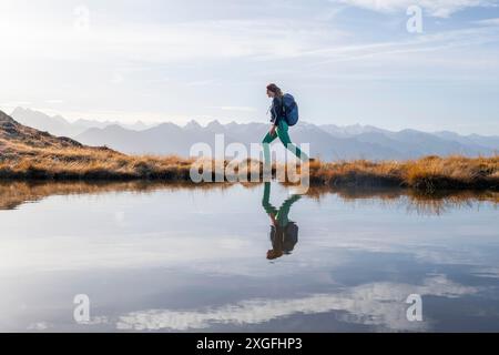 Escursionista riflesso in un piccolo lago di montagna sul Krahberg, panorama montano in autunno, attraversamento di Venet, Alpi Oetztal, Tirolo, Austria Foto Stock