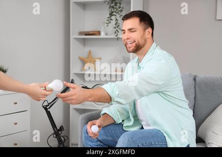 Giovane uomo che prende la lampadina da una donna a casa Foto Stock