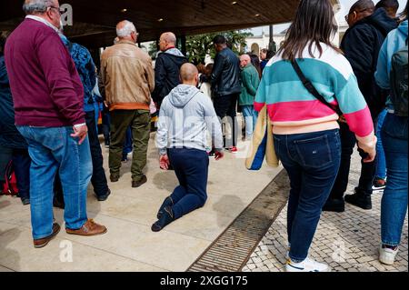 Uomo calvo di mezza età mentre strizza in ginocchio attraverso la folla fuori dalla cappella delle apparizioni Foto Stock