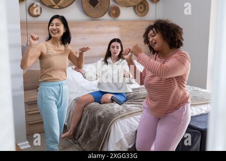 Ballando e divertendosi, tre amiche donne si divertono insieme in camera da letto Foto Stock