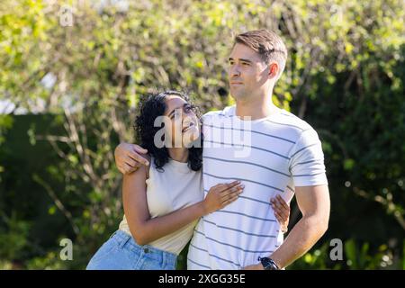 Giovani coppie che abbracciano e si divertono insieme all'aperto in giardino Foto Stock